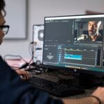 A video editor working on a project using a desktop computer in a modern office setting.